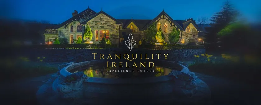 Tranquility Ireland logo over an illuminated stone house and fountain