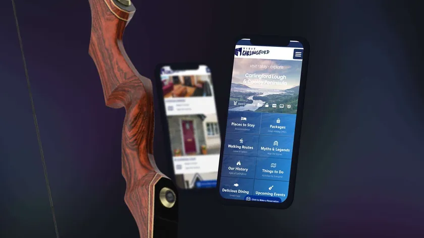 Visit Carlingford tourism website on smartphones beside a wooden bow