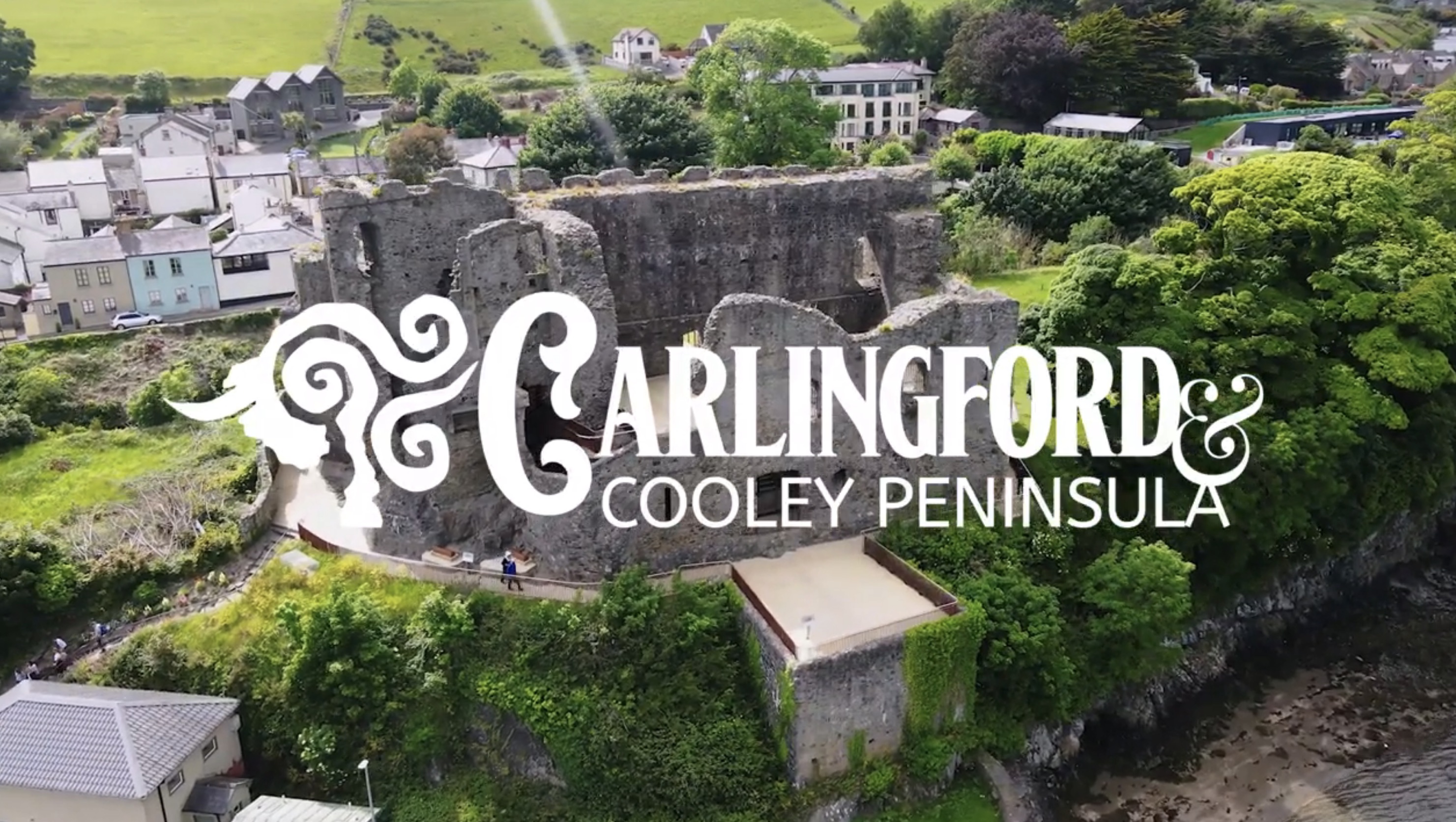 Carlingford and Cooley Peninsula white logo over aerial castle ruins